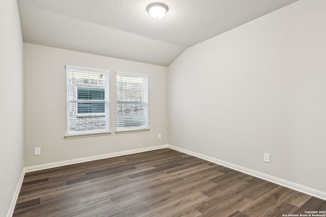 spare room with lofted ceiling, dark hardwood / wood-style floors, and a textured ceiling