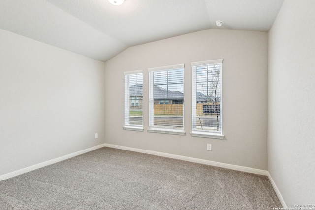 empty room featuring vaulted ceiling and carpet flooring