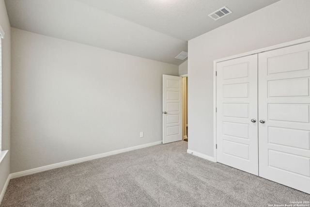 unfurnished bedroom featuring vaulted ceiling, light colored carpet, and a closet