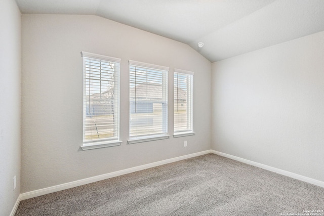 carpeted empty room with vaulted ceiling