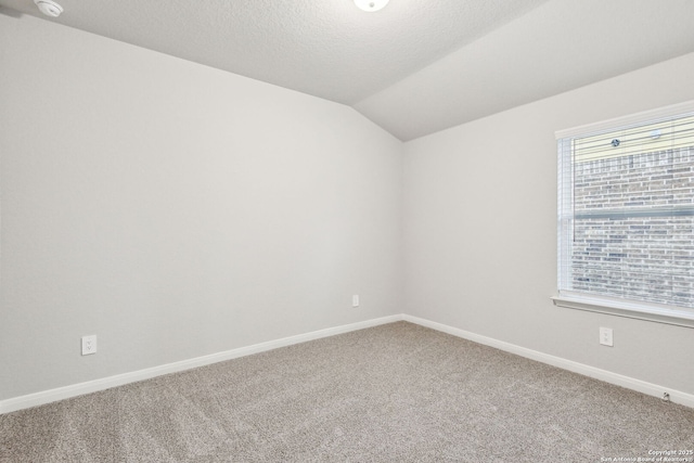 spare room featuring vaulted ceiling, carpet, and a textured ceiling