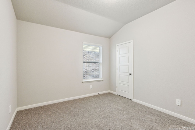 carpeted empty room featuring lofted ceiling and a textured ceiling