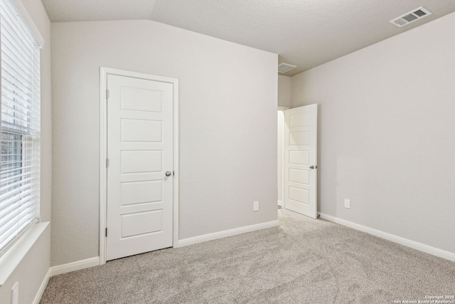 spare room with light colored carpet and vaulted ceiling