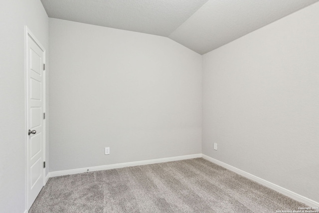 carpeted spare room with vaulted ceiling and a textured ceiling