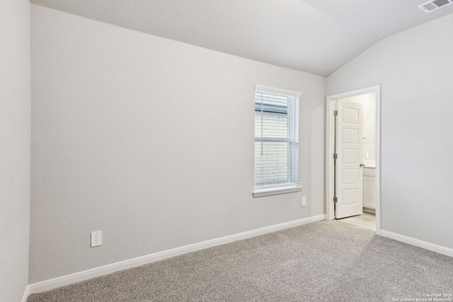 carpeted spare room featuring vaulted ceiling