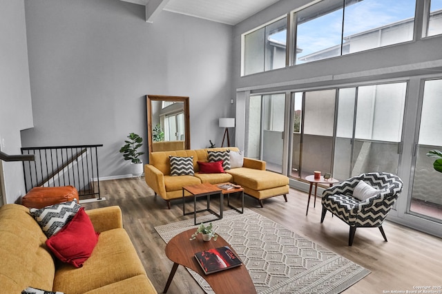 living room featuring hardwood / wood-style floors, a towering ceiling, and beamed ceiling