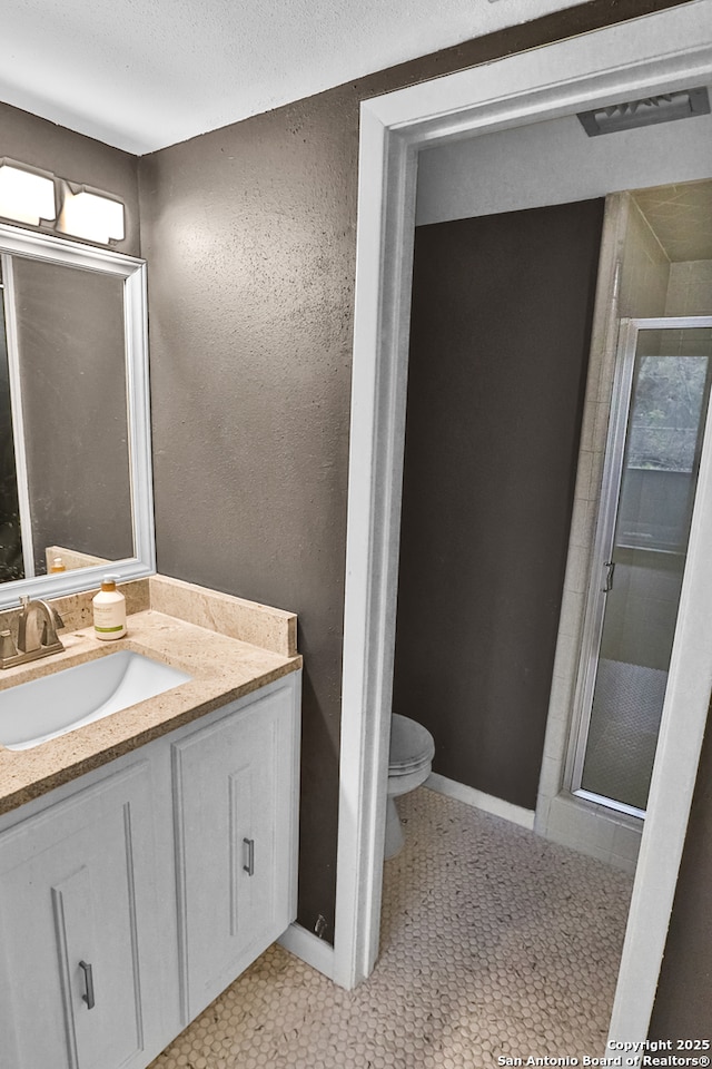 bathroom featuring tile patterned floors, a textured ceiling, toilet, walk in shower, and vanity