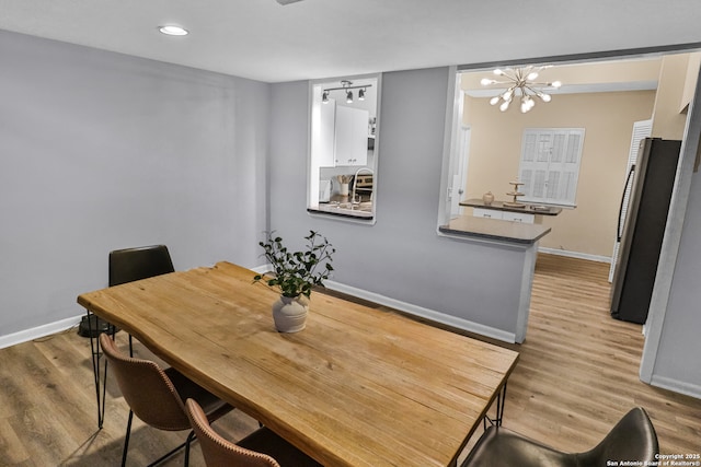 dining space with light hardwood / wood-style flooring and a notable chandelier