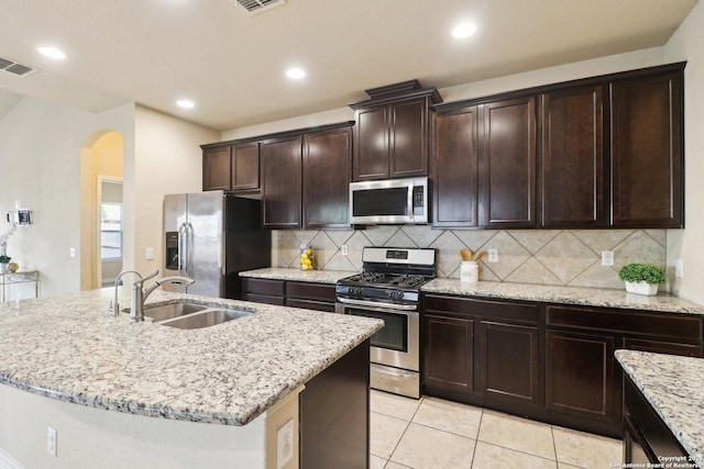 kitchen with sink, an island with sink, backsplash, and stainless steel appliances