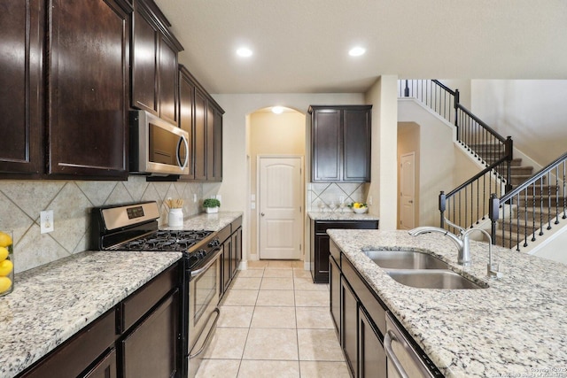 kitchen with sink, tasteful backsplash, light stone countertops, light tile patterned flooring, and stainless steel appliances