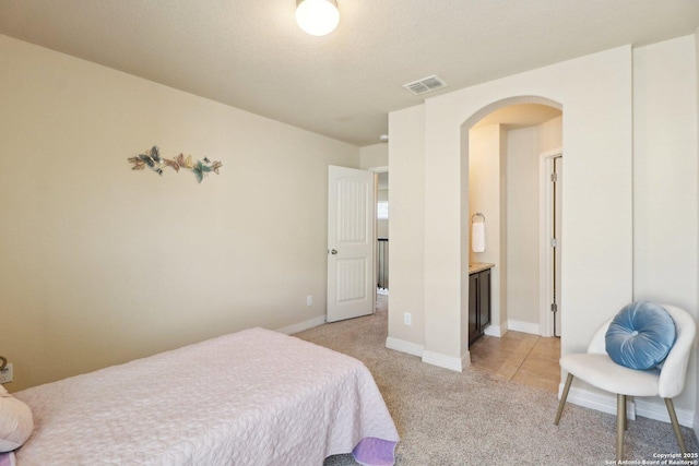 bedroom with light colored carpet and connected bathroom