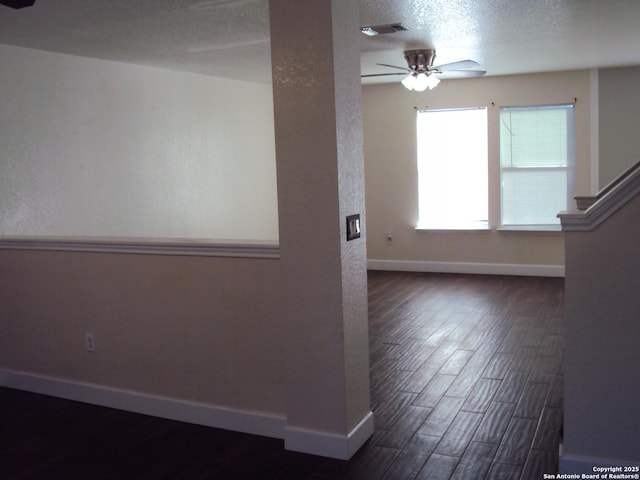 empty room featuring ceiling fan, a textured ceiling, and dark hardwood / wood-style flooring