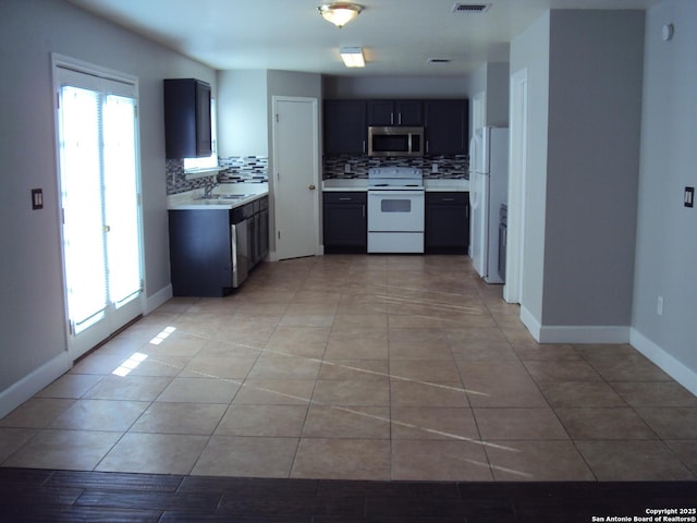 kitchen featuring sink, light tile patterned flooring, white appliances, and tasteful backsplash