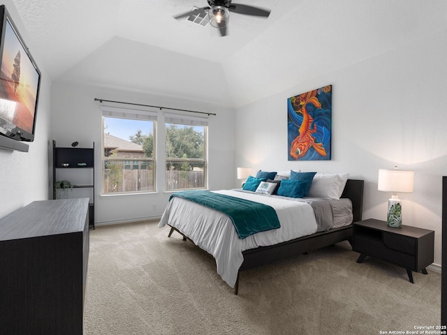 carpeted bedroom with vaulted ceiling, ceiling fan, and a tray ceiling