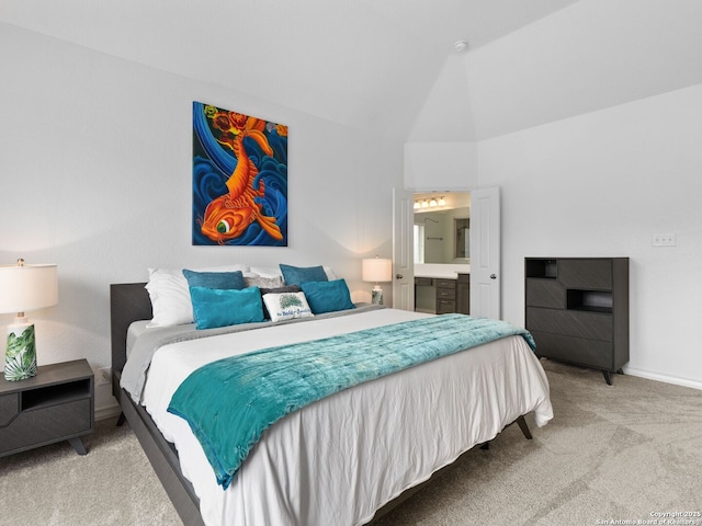 carpeted bedroom featuring ensuite bath and vaulted ceiling