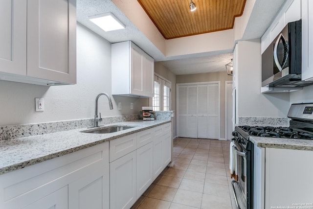 kitchen with light stone countertops, white cabinets, appliances with stainless steel finishes, sink, and wooden ceiling