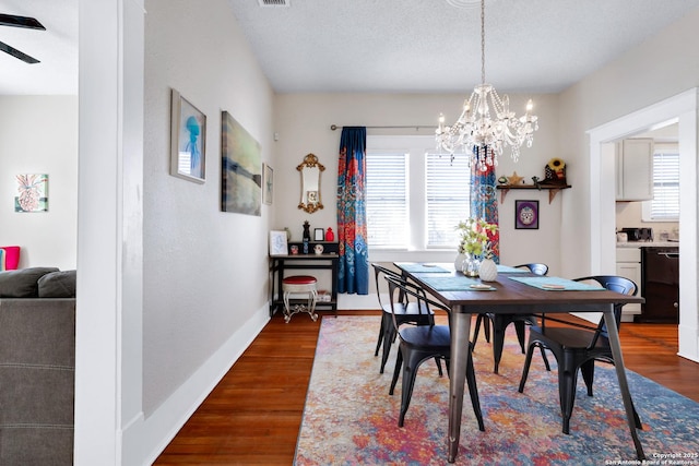 dining room featuring dark wood-type flooring, a textured ceiling, a wealth of natural light, and an inviting chandelier