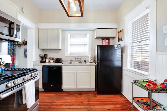 kitchen featuring black appliances, white cabinets, plenty of natural light, and sink