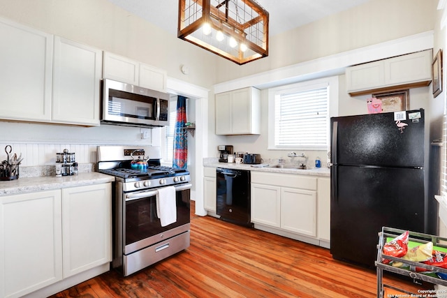 kitchen featuring black appliances, light hardwood / wood-style flooring, white cabinets, and sink