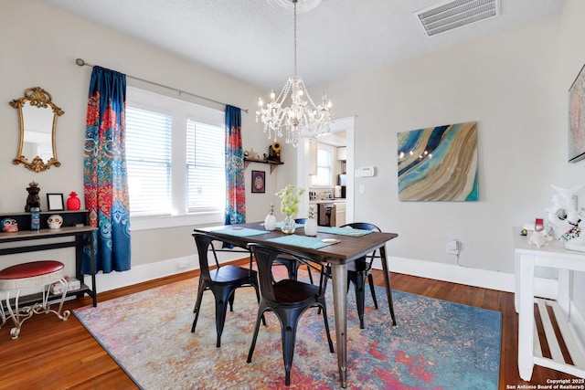 dining area with wood-type flooring and a notable chandelier