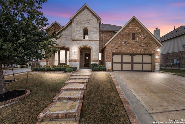 french country inspired facade featuring a yard and a garage