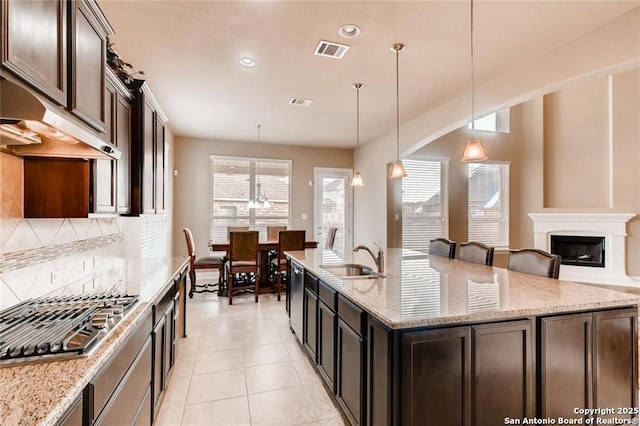 kitchen featuring sink, pendant lighting, light stone countertops, and stainless steel appliances