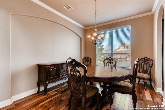 dining space featuring hardwood / wood-style flooring, crown molding, and an inviting chandelier