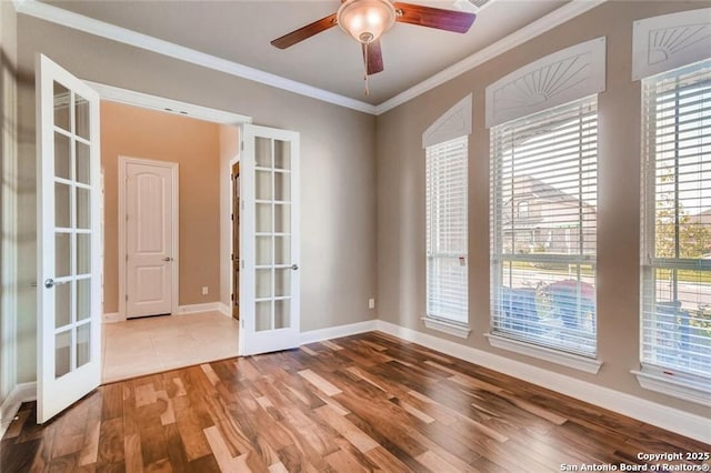 empty room featuring crown molding, hardwood / wood-style floors, ceiling fan, and french doors