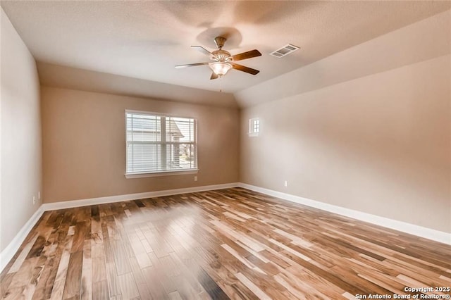 spare room featuring wood-type flooring, vaulted ceiling, and ceiling fan