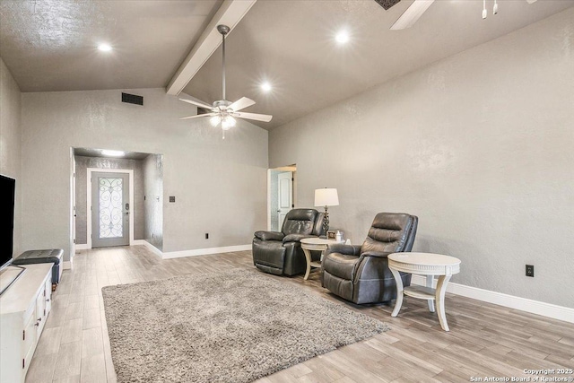 sitting room featuring ceiling fan, high vaulted ceiling, beamed ceiling, and light wood-type flooring