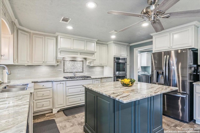 kitchen with sink, stainless steel appliances, light stone counters, and separate washer and dryer