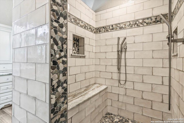 bathroom featuring a tile shower and wood-type flooring