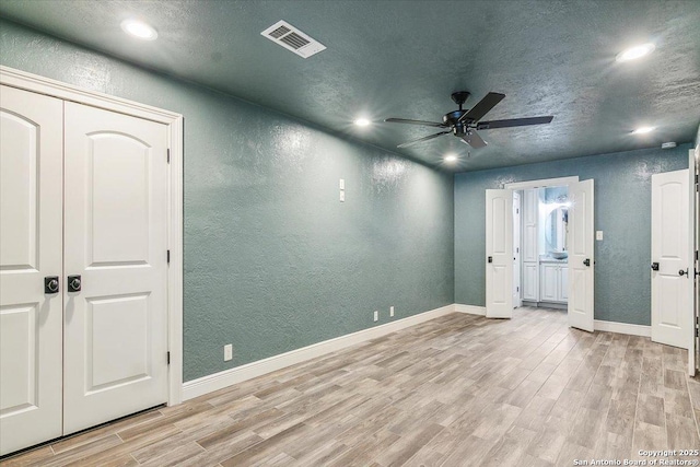 empty room with light wood-type flooring, a textured ceiling, and ceiling fan