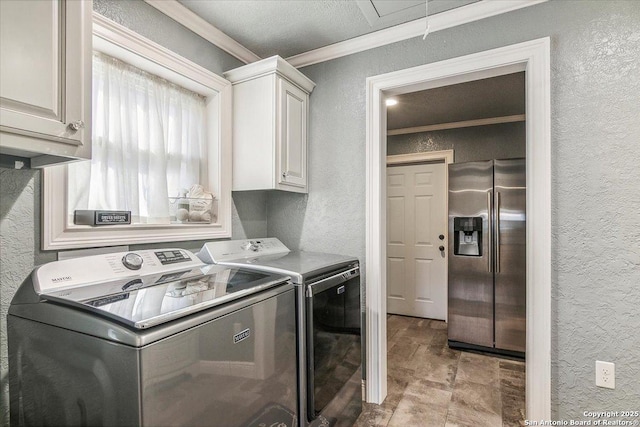 clothes washing area featuring crown molding, cabinets, and washing machine and dryer