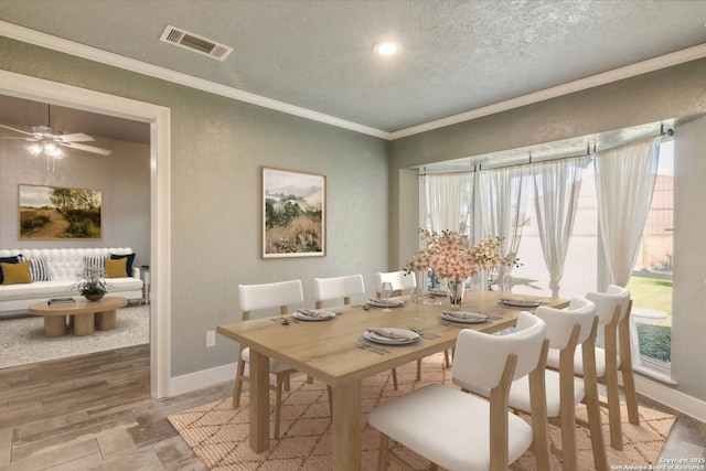 dining room with ceiling fan, a textured ceiling, and ornamental molding