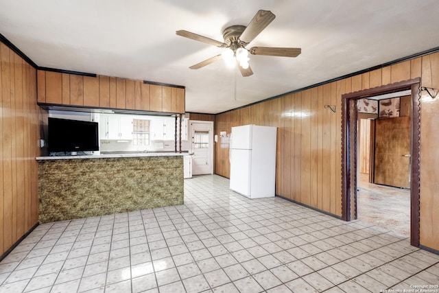 kitchen featuring wood walls, white refrigerator, kitchen peninsula, and ceiling fan