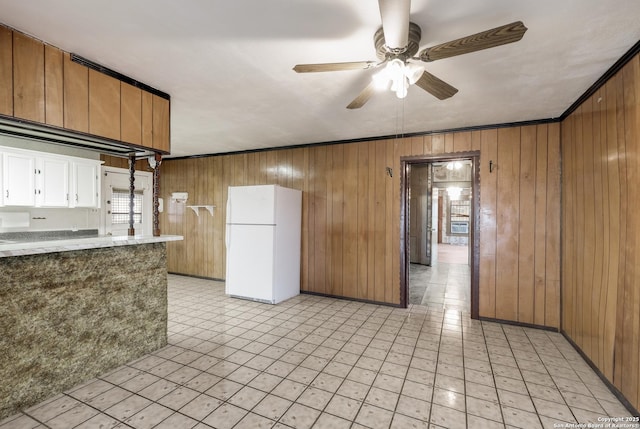 kitchen featuring ornamental molding, wood walls, ceiling fan, and white fridge