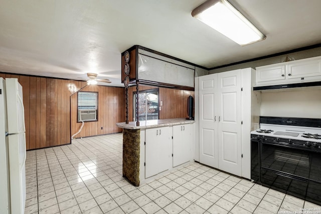 kitchen with white cabinetry, white fridge, range with gas cooktop, ceiling fan, and wood walls