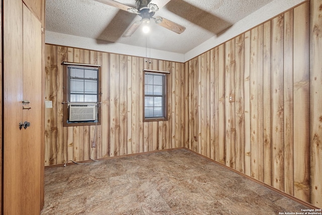 unfurnished room featuring a textured ceiling, wooden walls, cooling unit, and ceiling fan