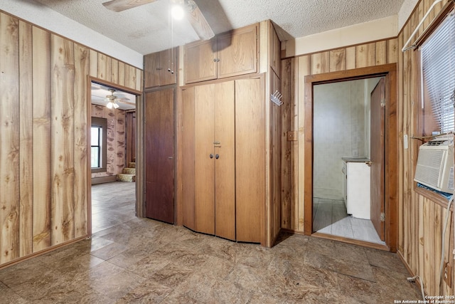 hall with a textured ceiling and wooden walls