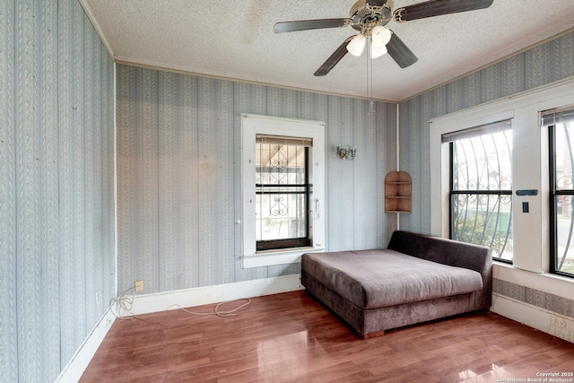 bedroom featuring ceiling fan, hardwood / wood-style floors, ornamental molding, and a textured ceiling