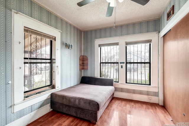 living area with hardwood / wood-style flooring, a textured ceiling, and ceiling fan