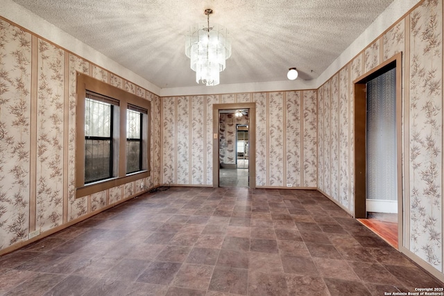 spare room with a textured ceiling and a chandelier