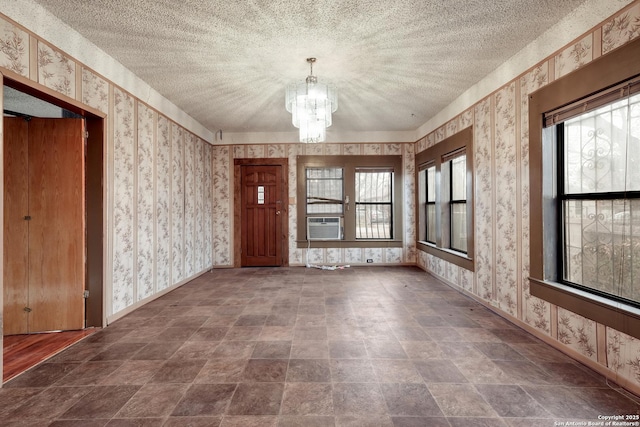 unfurnished room with a textured ceiling, a chandelier, and cooling unit