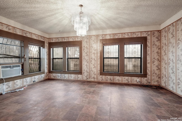 spare room featuring a textured ceiling, cooling unit, and a chandelier