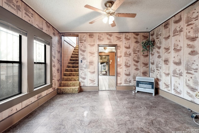 spare room featuring a textured ceiling, crown molding, heating unit, and wood walls