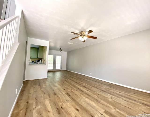 unfurnished living room with light hardwood / wood-style floors, ceiling fan, and french doors