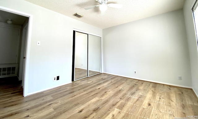 unfurnished bedroom featuring ceiling fan, a textured ceiling, a closet, and light hardwood / wood-style flooring