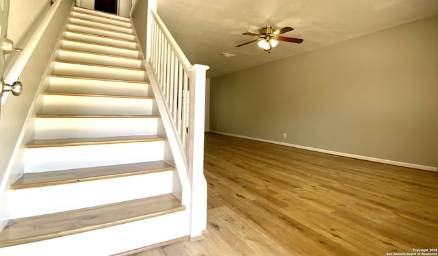 staircase with ceiling fan and hardwood / wood-style floors