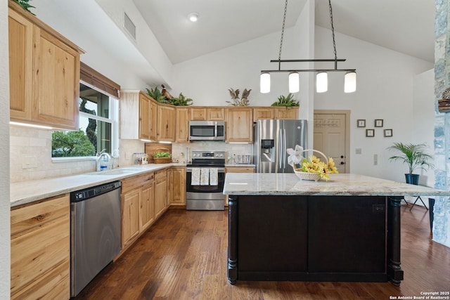 kitchen with sink, backsplash, a kitchen island, and appliances with stainless steel finishes